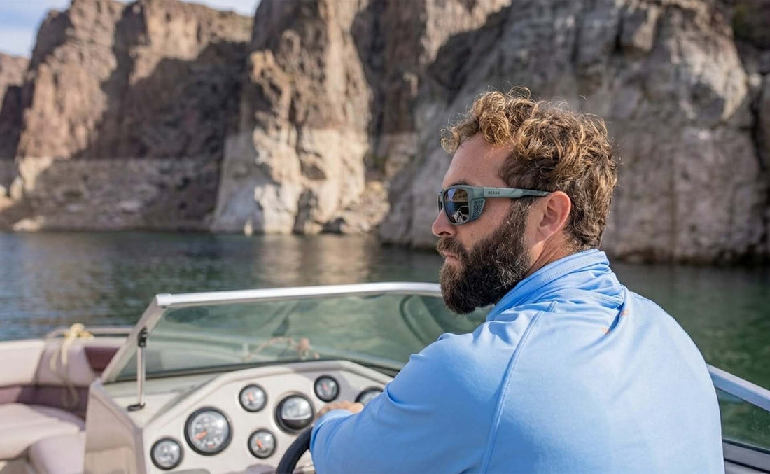 Man steering a boat past sea cliffs wearing Ocean watersport sunglasses
